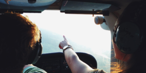 pilots in plane pointing at sky