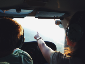 pilots in plane pointing at sky 